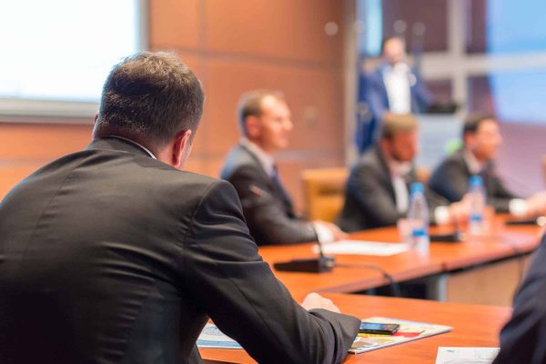 Manager giving a talk on corporate business event. Company managemant taking decisions at board room. Business and Entrepreneurship event. Focus on unrecognizable businessman in front.